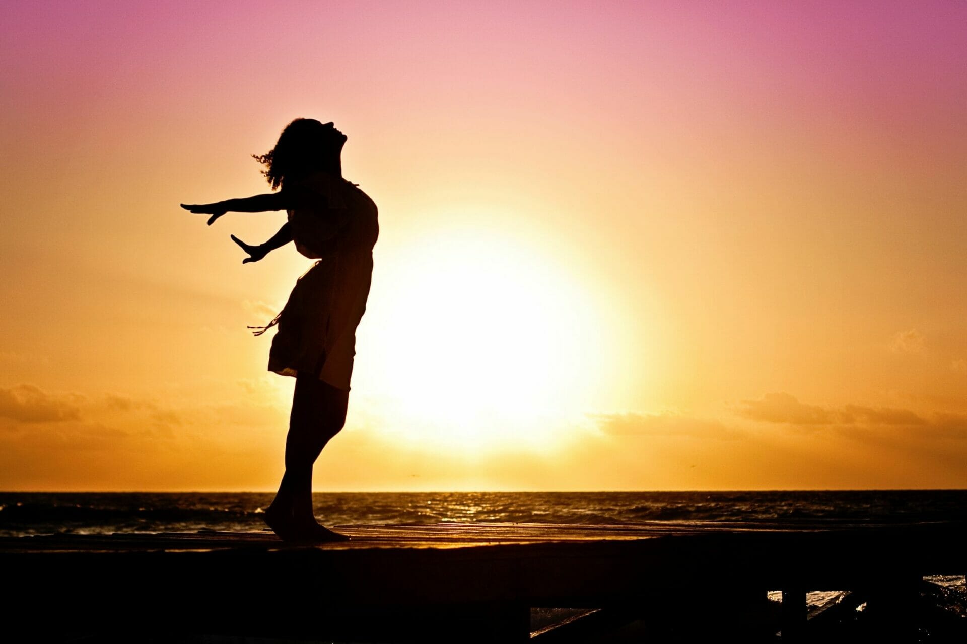 Woman feeling the sea air at the beach at sunset - Build Your Confidence One Moment at a Time