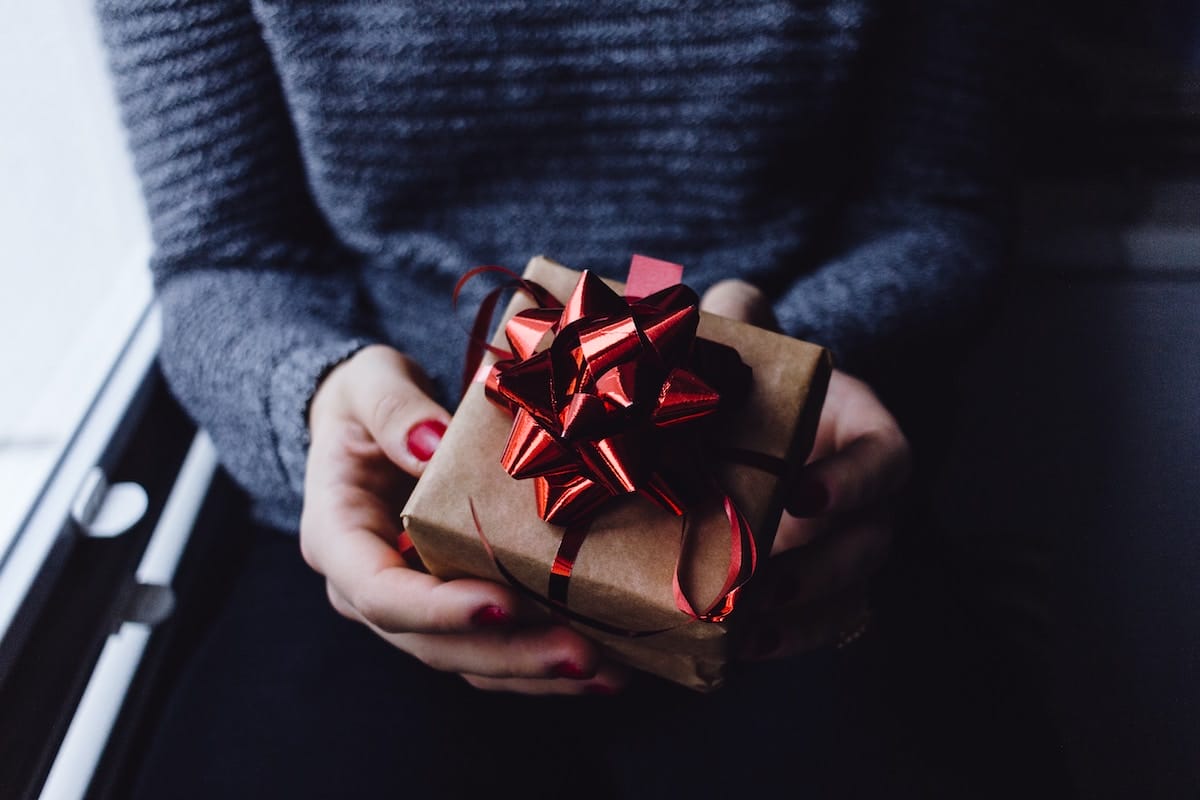 woman's-hands-holding-a-small-package-with-red-bow