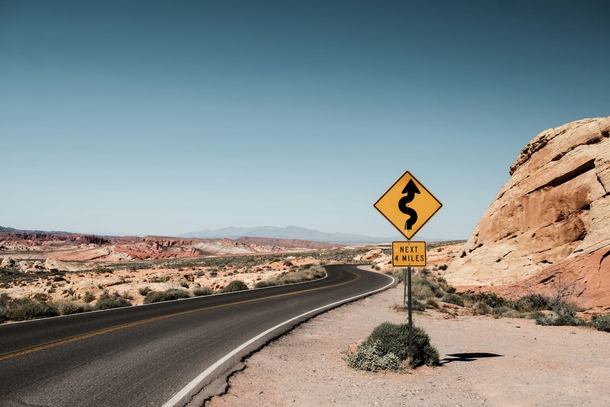 road sign in the desert saying there is a winding road ahead