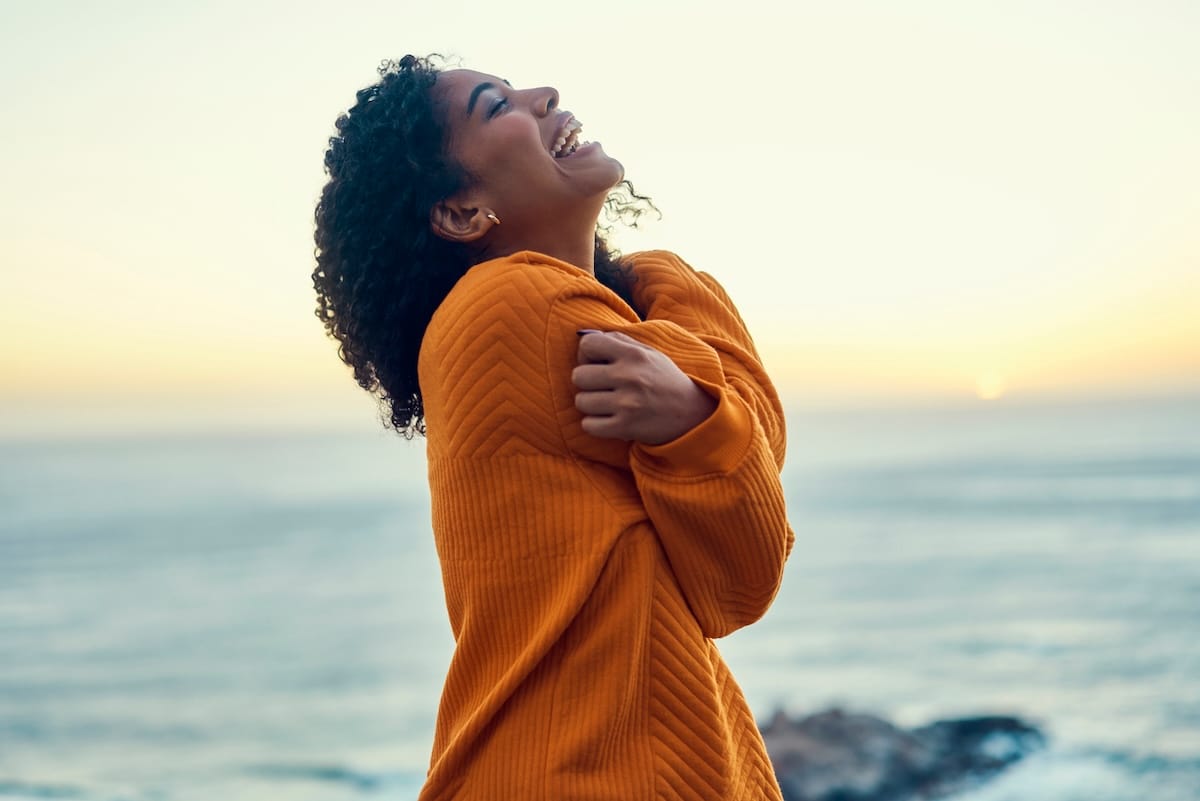 Woman hugging herself and smiling up at thee sky