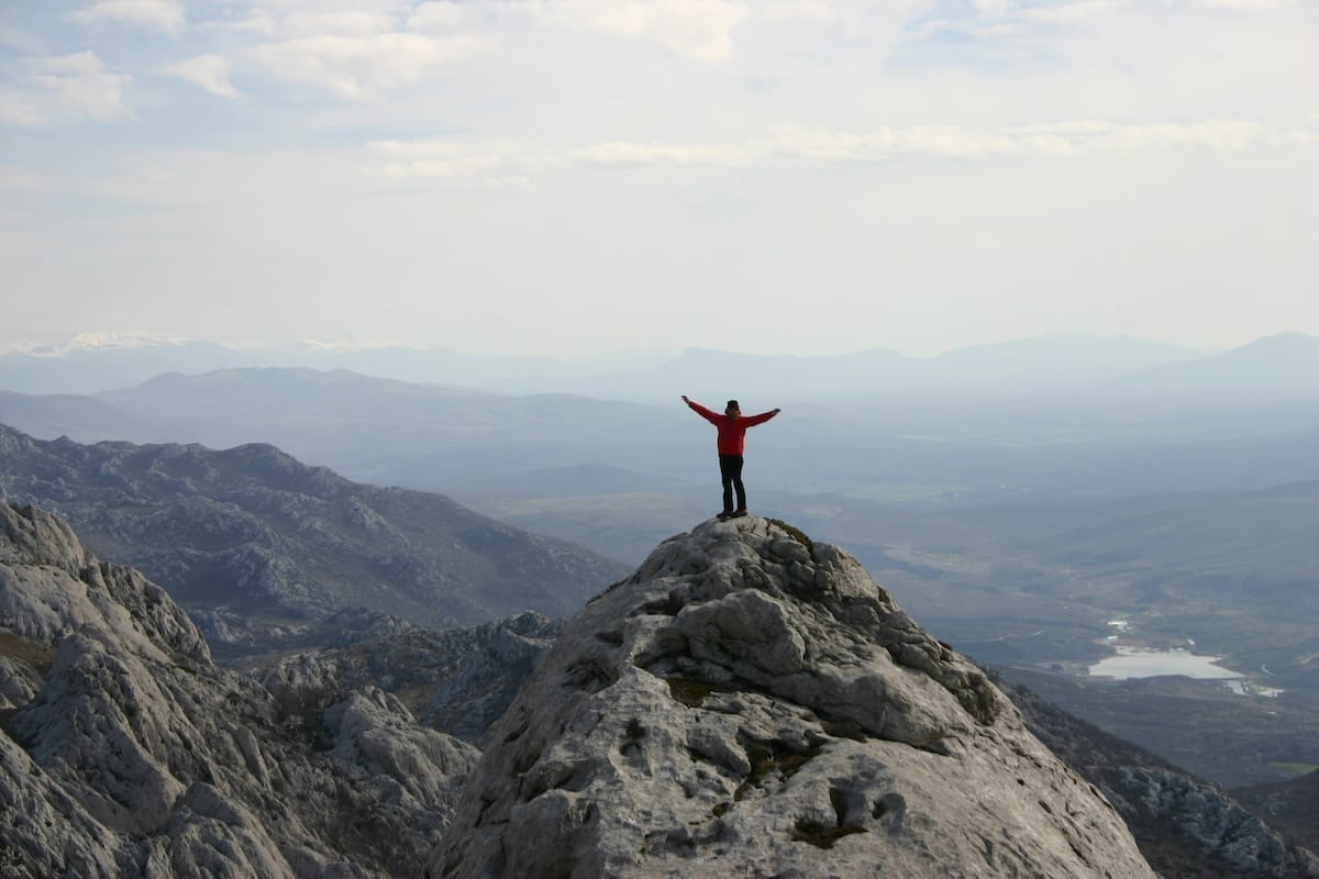 Man standing on top of mountain with his hands in the air