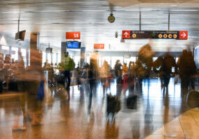 Airline Passengers are blurred in motion inside a busy terminal at the Seattle Airport.